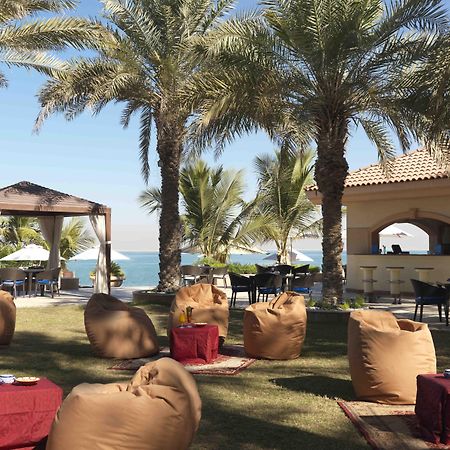 Al Raha Beach Resort & Spa Abu Dhabi Restaurant bilde The photo depicts a beautiful outdoor setting with several elements of relaxation and leisure. In the foreground, there are large, comfortable bean bag chairs arranged on a grassy area, accompanied by low tables. Surrounding this seating area are tal