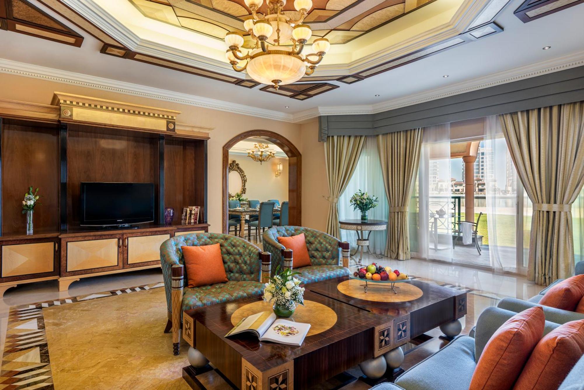 Al Raha Beach Resort & Spa Abu Dhabi Eksteriør bilde The photo depicts a luxurious living room with elegant decor. It features two green upholstered sofas accented with orange pillows, arranged around a stylish coffee table. The coffee table showcases decorative items, including a magazine and a bowl o