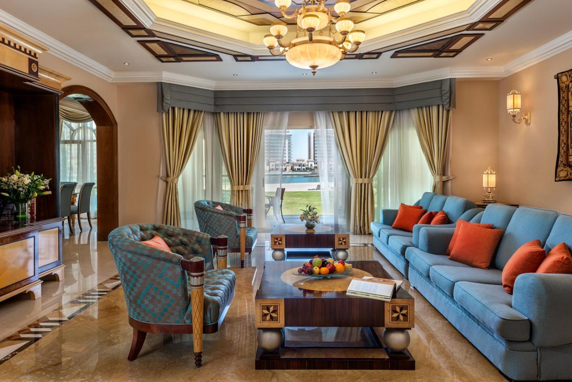 Al Raha Beach Resort & Spa Abu Dhabi Eksteriør bilde The photo depicts an elegantly designed living room with a sophisticated atmosphere. It features a large, light blue sofa adorned with orange and blue cushions. There are two stylish armchairs nearby with a unique pattern. In the center, a coffee tab