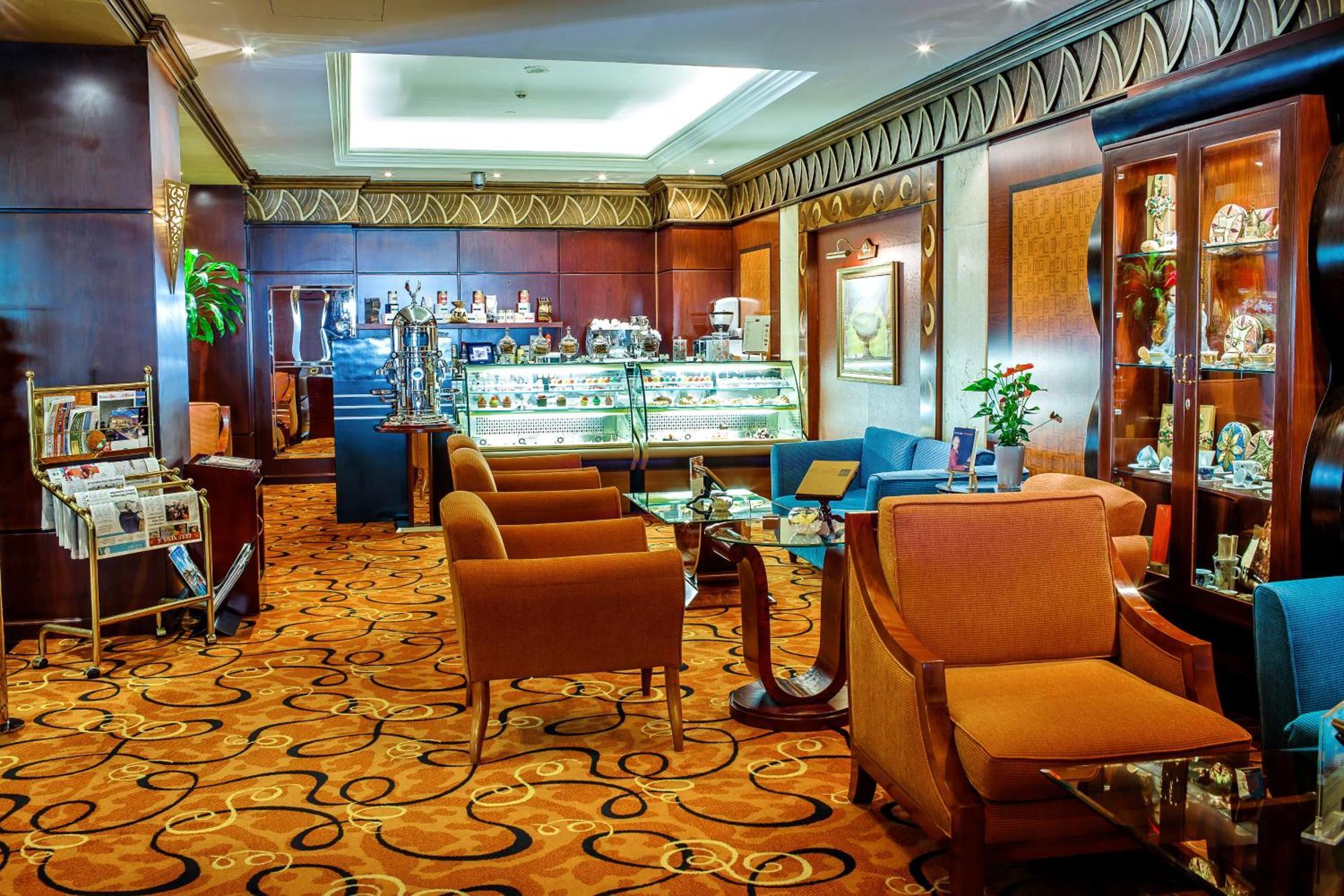Al Raha Beach Resort & Spa Abu Dhabi Eksteriør bilde The photo shows a cozy and elegantly designed lounge or café area. It features plush seating with brown armchairs and a blue couch. In the background, there is a display case filled with various items, likely including pastries or decorative goods. T